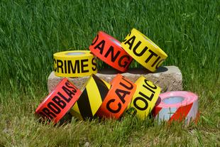 Various caution tapes on grass and bricks.